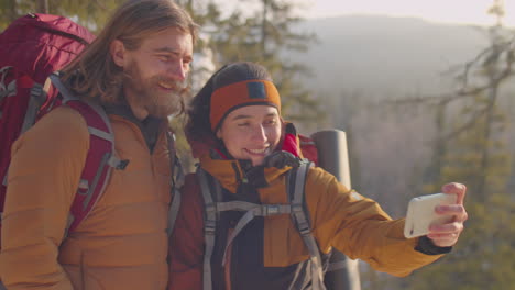 couple taking selfie on mountain top during winter hike