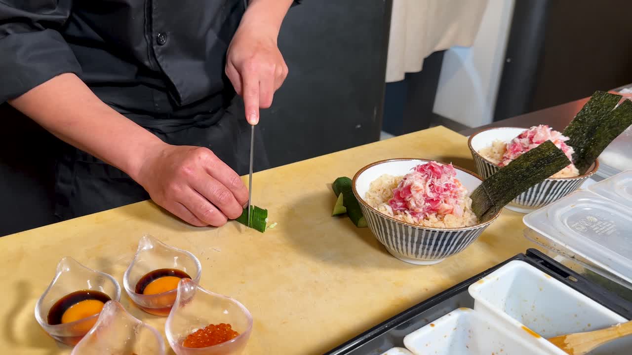 Uno chef professionista in uniforme nera taglia con cura un cetriolo su un bancone di legno