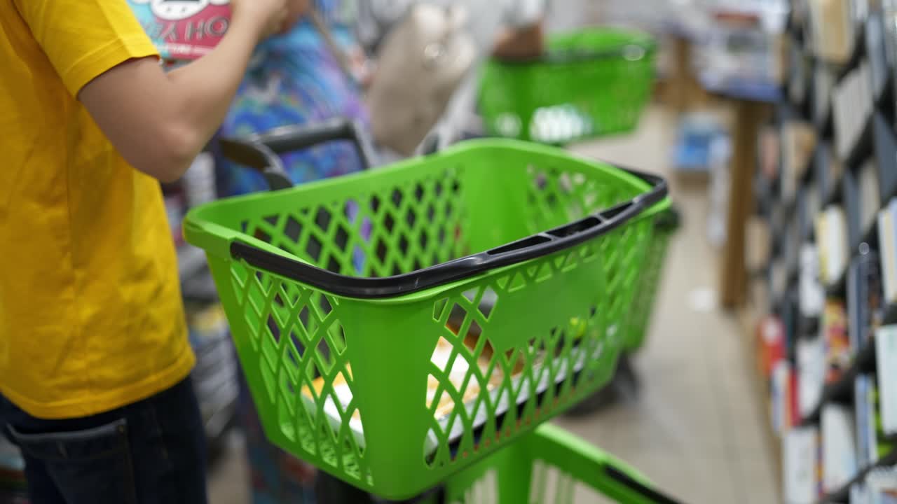 Boy choosing school supplies. Shopping cart with school supply