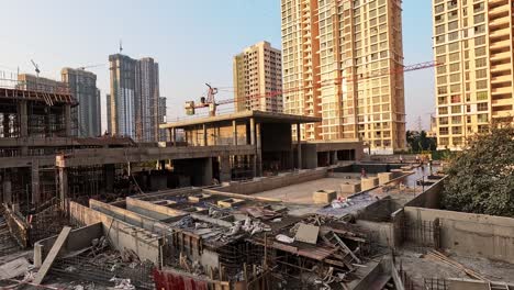 High-rise-construction-site-with-building-materials,-towering-cranes-and-machinery