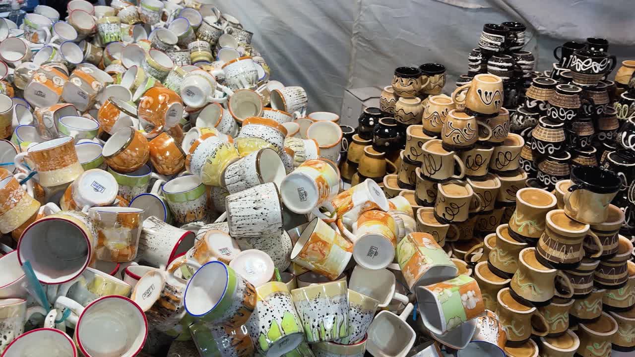 large pile of colorful ceramic coffee mugs stacked in bulk display