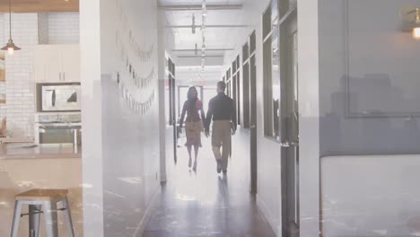 male and female business people walking through office corridor, over cityscape