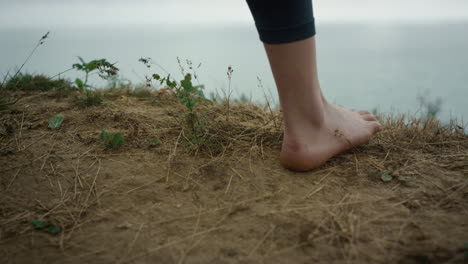 closeup woman feet standing tophill. unknown barefoot girl stop on dry grass.