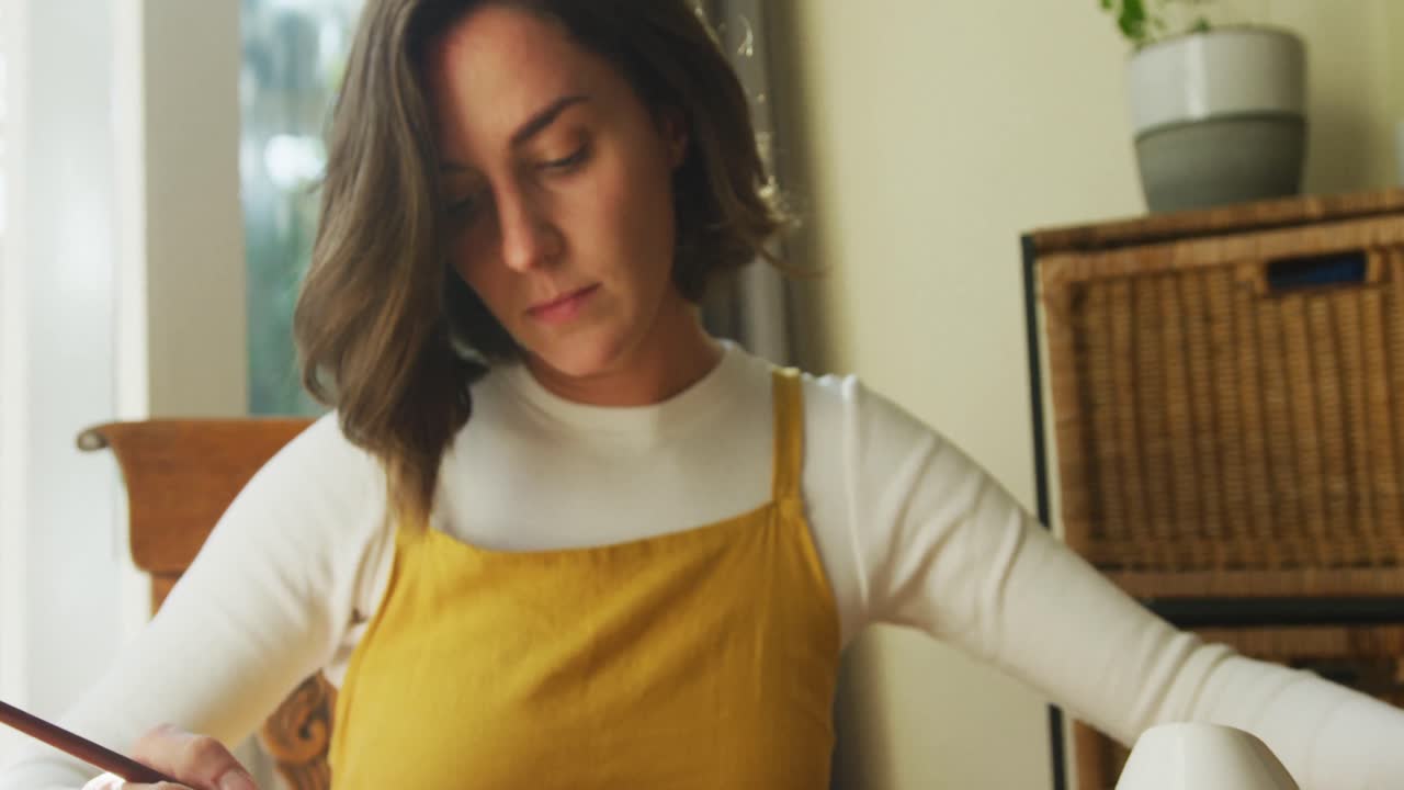 Caucasian woman with brown hair painting at home