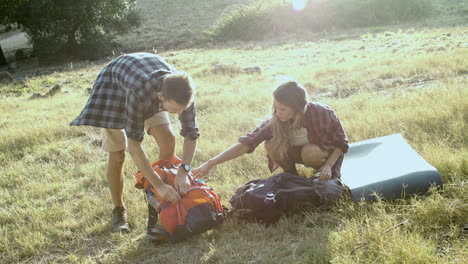 un par de excursionistas desempacando mochilas en el césped