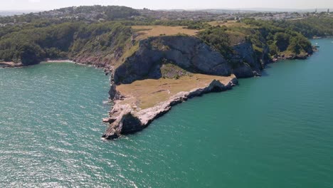 toma aérea panorámica del famoso punto de cantera largo en una colina alta rodeada de agua verde azul del océano bajo el sol
