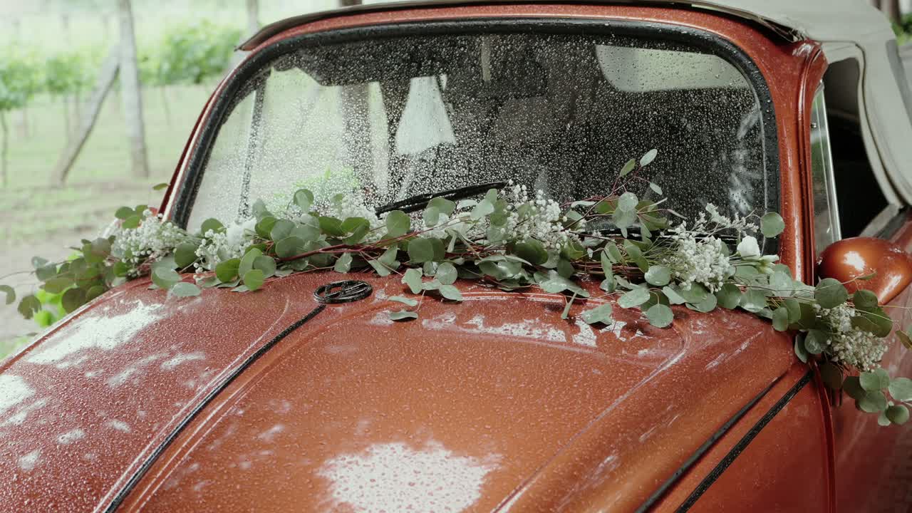 classic car hood with green bouquet under soft rain on wedding day