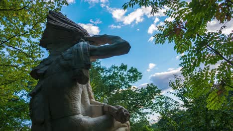 Bezaubernder-Zeitraffer-Einer-Lenape-Statue-Mit-Ziehenden-Wolken-Und-Sonnenschein-In-Den-Ruhigen-Wäldern-Von-Philadelphia