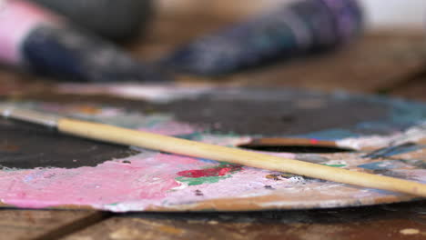 Close-up-of-paint-brush-on-artist's-colour-palette-with-mixed-paints