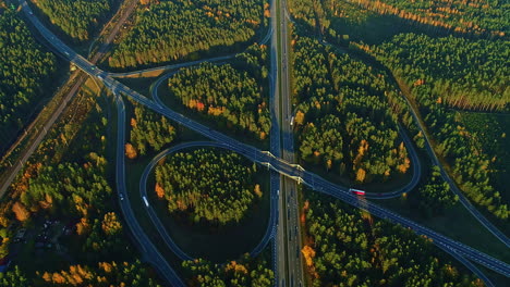 a large highway cloverleaf interchange in a forested setting in autumn - aerial time lapse