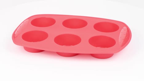 forma de silicona roja para cocinar muffins y cupcakes sobre fondo blanco. vista lateral. movimiento en bucle. rotación 360.