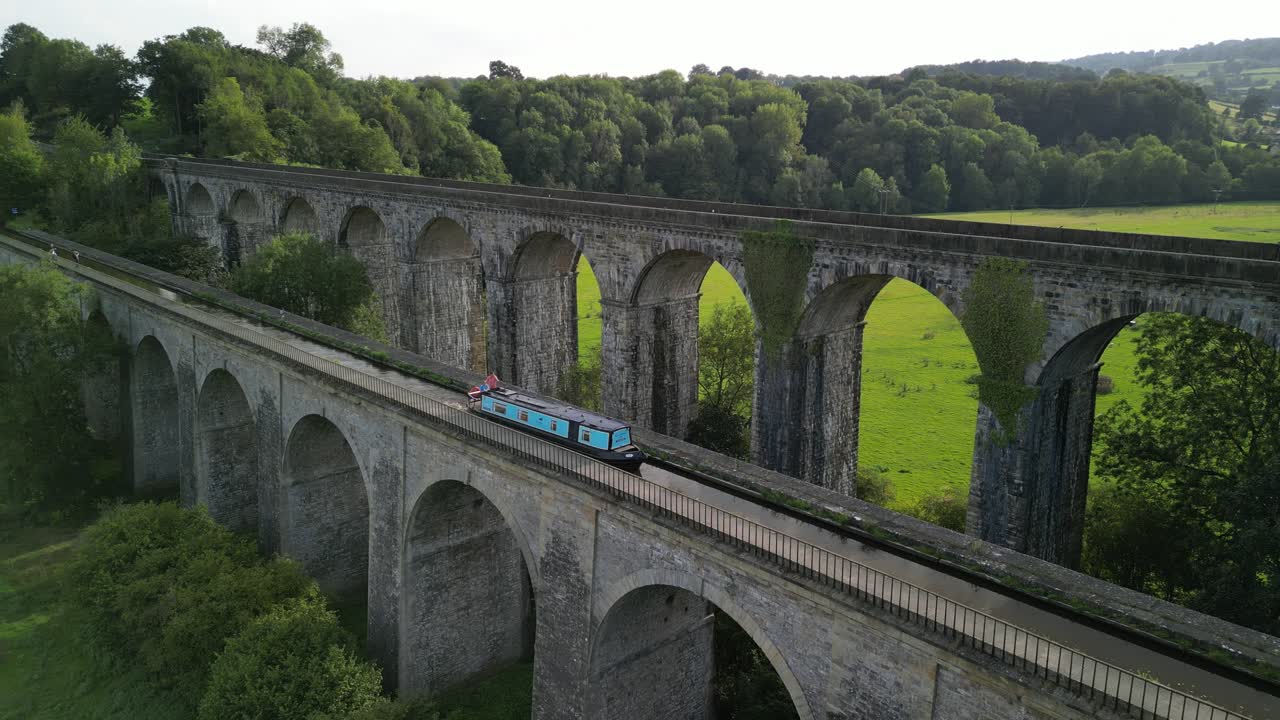 Narrowboat crossing canal over Chirk Aqueduct, Railway Viaduct in background - stationary aerial drone - Welsh, English border, Sept 23
