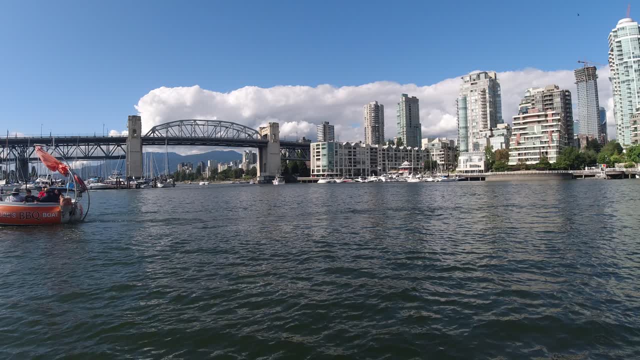 birds fly over a reflective ocean harbor of Granville Island, yaletown, the burrard bridge with whale watching boats docking, big group on bbq boat passes by the most modern architecture of towers2-2