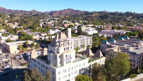 aerial over the hollywood tower hotel reveals the griffith park observatory and hollywood sign distant