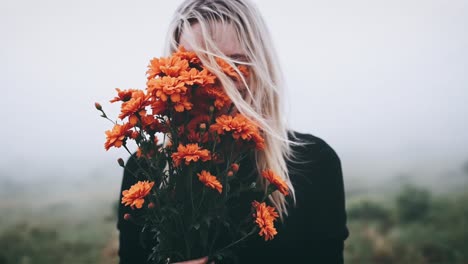woman hiding face in a bouquet of orange flowers