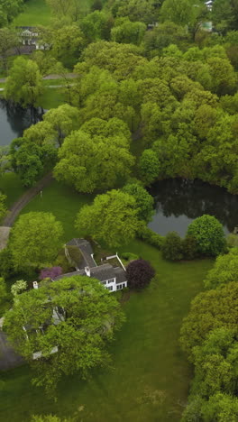 green rural suburb with beautiful houses on the distance from each other. lovely residential area with little ponds by the mansions. top view. vertical video