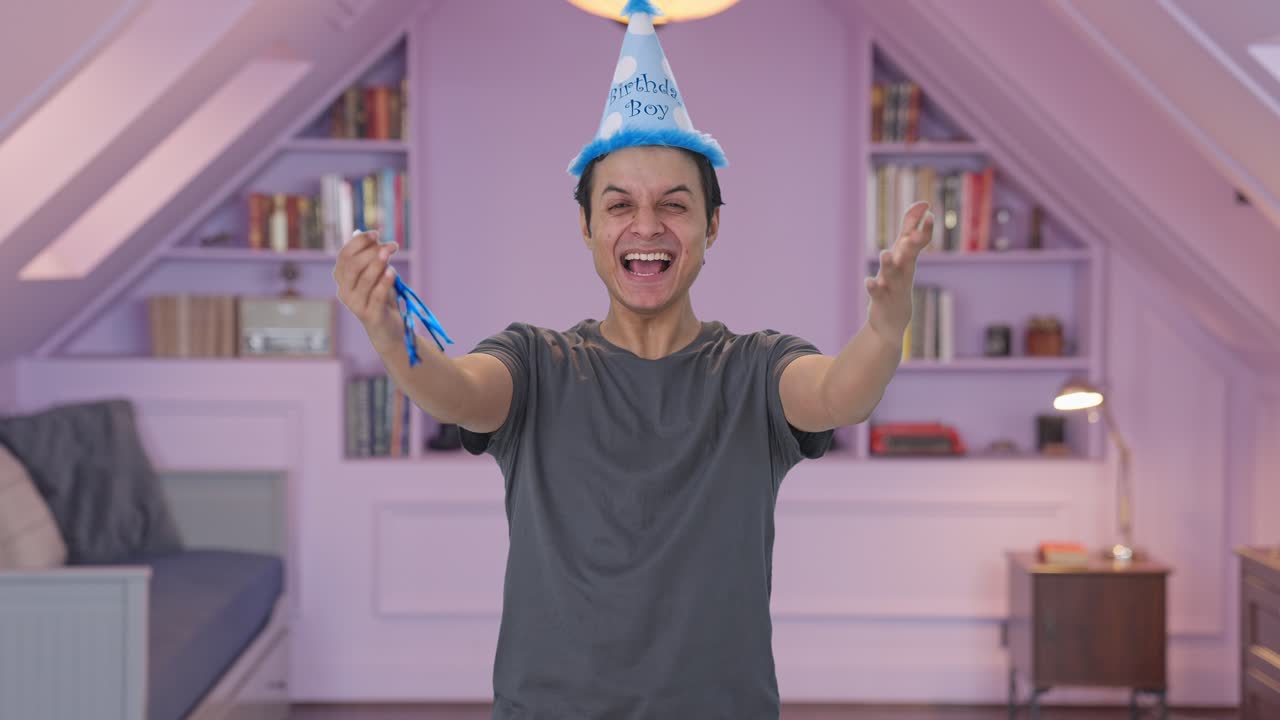 Uomo indiano felice che soffia una trombetta da compleanno