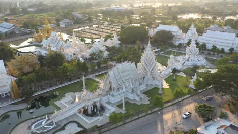 aerial of wat rong khun the giant buddhist white temple and golden temple with mountains and landscape in chiang rai, thailand