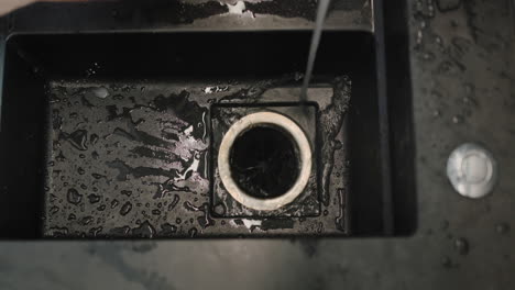 man throwing food waste into the garbage disposal in the kitchen sink. top view