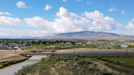 Aerial-hyperlapse-of-a-highway-and-a-river-flowing-towards-a-distant-mountain-range