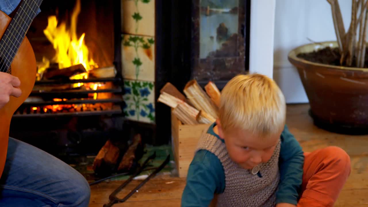 아버지 는 아들 에게 집 의 거실 에서 기타 를 연주 하는 법 을 가르치고 있다 4k