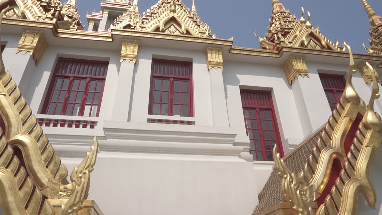 Slow Motion clip walking under a gold and white buddhist temple pointing up of a popular travel destination in the city of Bangkok in Thailand