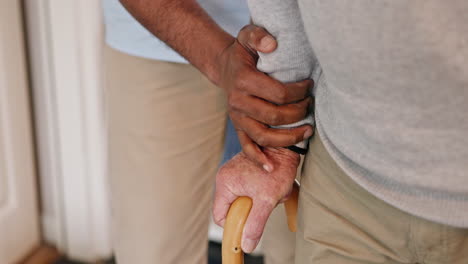 close-up of caregiver assisting senior with walking cane