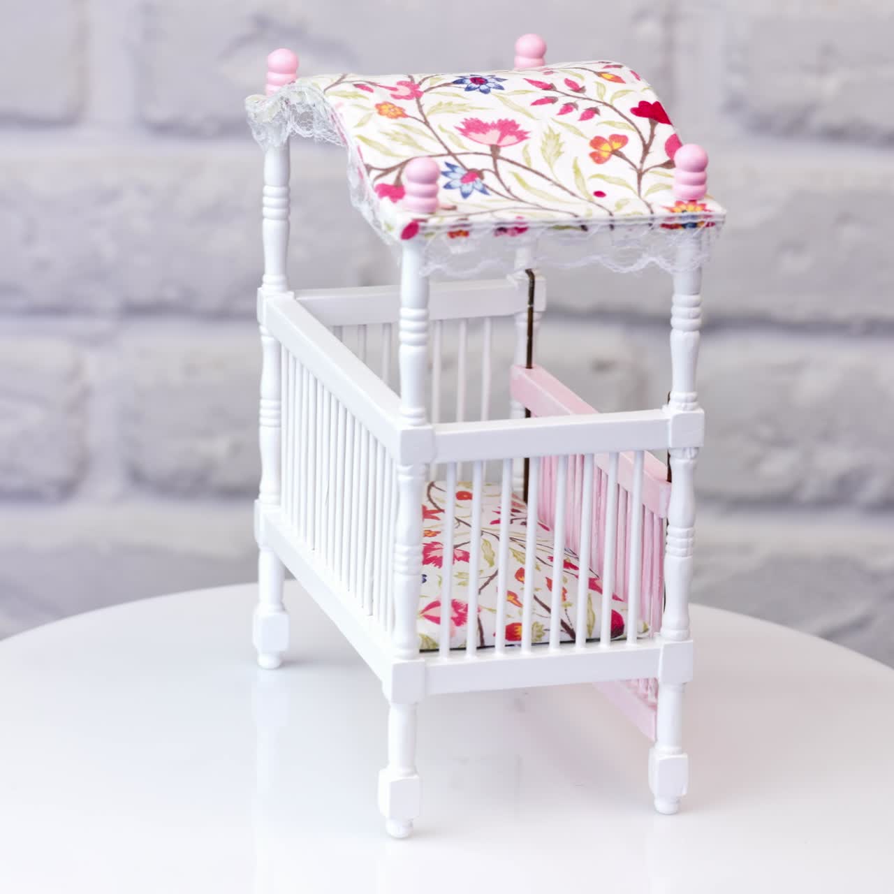 Tiny baby crib rotating on the table. Curved little bed with colorful mattress and top close up