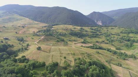 aerial: flying over arable land in a mountainous area, mountains can be seen in the background