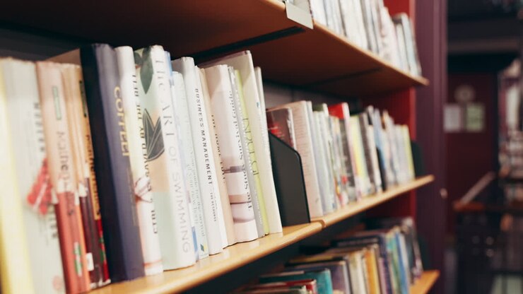 Una persona che sceglie un libro da uno scaffale in una biblioteca