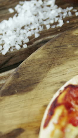 italian pizza on wooden table with vegetables and spices