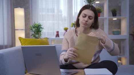 mujer joven sentada en casa leyendo un periódico serio e importante y estando conmocionada y frustrada.