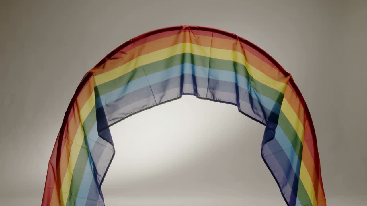 Vertical video: Sheer rainbow scarf arching and fluttering after gust, showing stripes for fashion