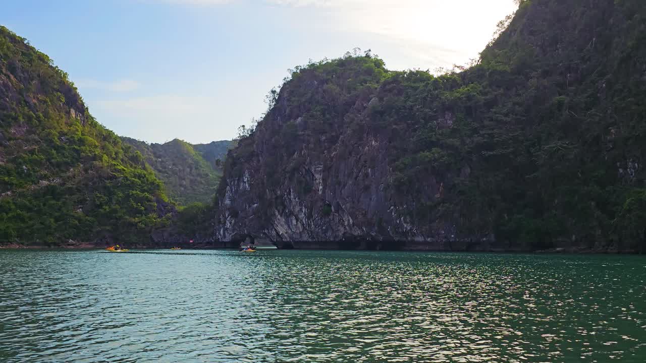 Ha Long Bay Tourists Kayaking Through Cave With Limestone Mountains Backdrop In Northeast Vietnam