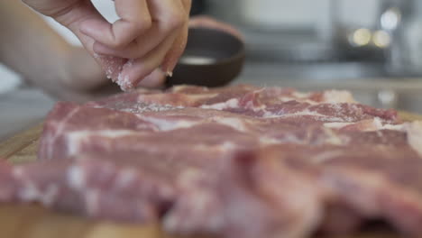 Primer-Plano-De-Los-Dedos-Poniendo-Sal-En-La-Carne-Cruda-En-La-Cocina