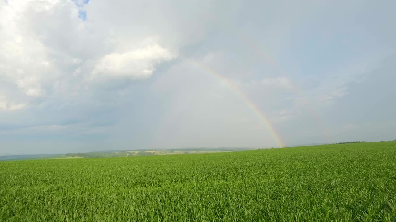 arco iris en un cielo nublado sobre un campo. vista aérea.