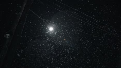 winter snowfall at night snowing on city street in street light
