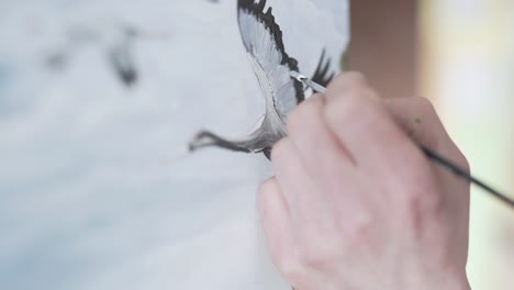 escena de primer plano de un pintor que está pintando un cuadro en un caballete