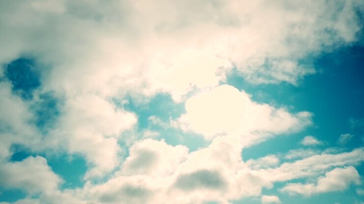 Slow-moving majestic clouds with sun behind and blue sky