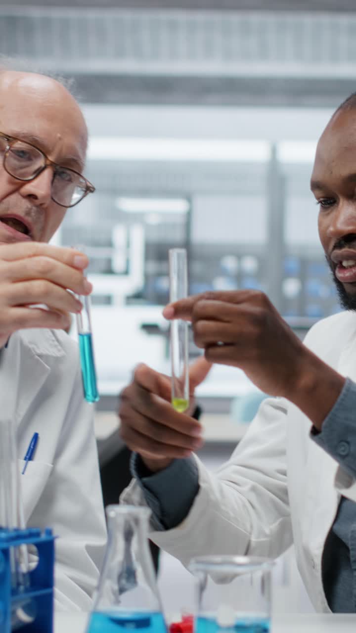Vertical video Teamworking molecular biologists in lab evaluate blue compound solution
