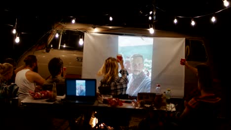 amigos viendo una película en la pantalla en el campamento