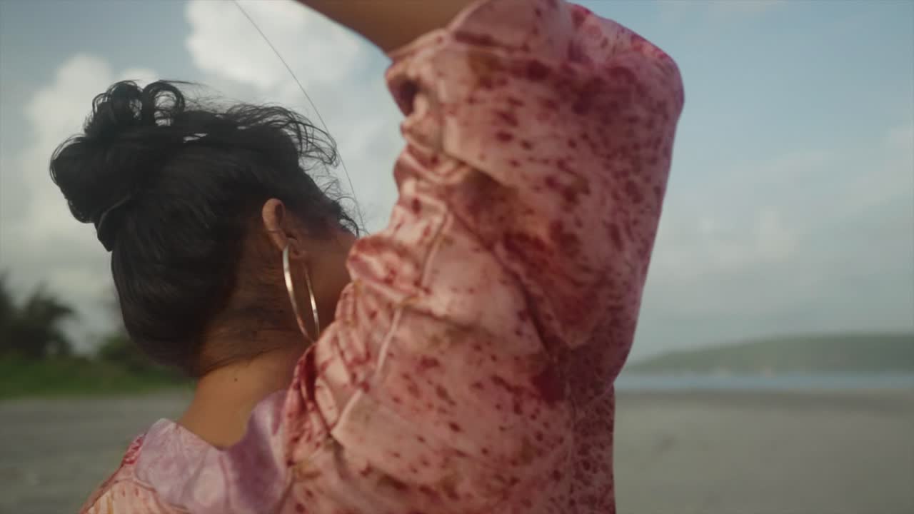 a beautiful shot of a stunning asian model in blood shed outfit and bun hair style enjoying cheerfully on a beach in a pleasant weather