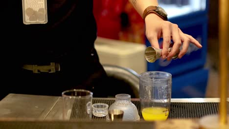 bartender pouring ingredients into a cocktail shaker