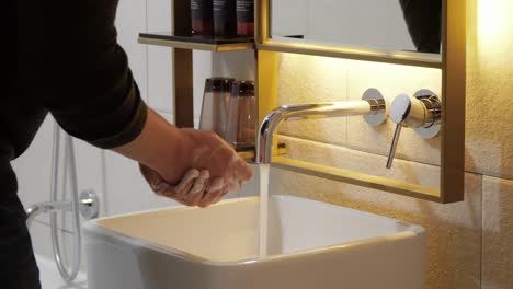 Man-washing-hands-with-soap-in-bathroom---hands-close-up