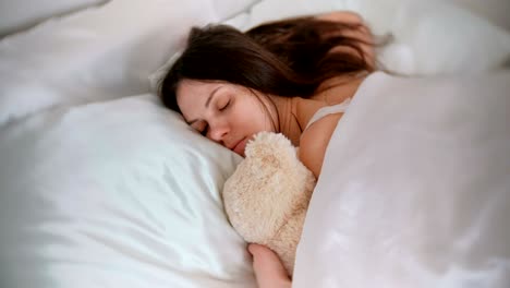 young woman sleeping with a toy bear.