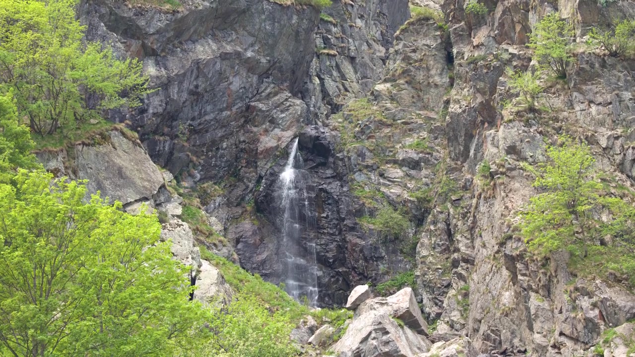 Una stretta cascata scorre giù da una scogliera montuosa scoscesa vicino a Entracque nelle Alpi italiane.