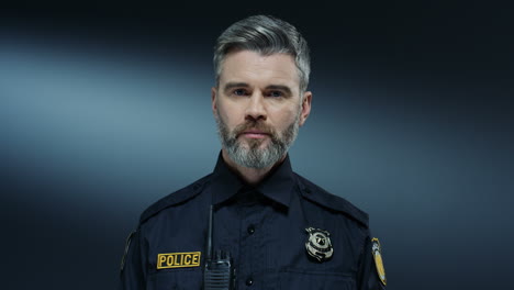 portrait shot of the good looking policeman with serious face and in the uniform looking straight to the camera