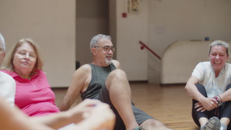 senior people sitting on floor in circle after workout