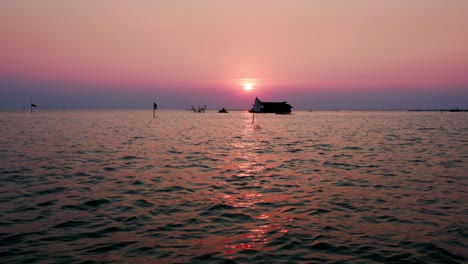 Tone-Sap,-Asias-biggest-lake-during-the-magical-reflective-orange-sun-set-with-house-boat-on-the-horizon