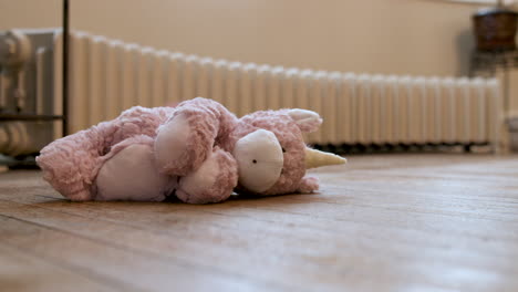 still shot of a baby toy unicorn sitting on the floor in front of a radiator in an old house